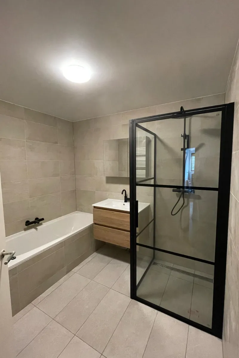 Moderne badkamer met ligbad en zwarte stalen douchewand